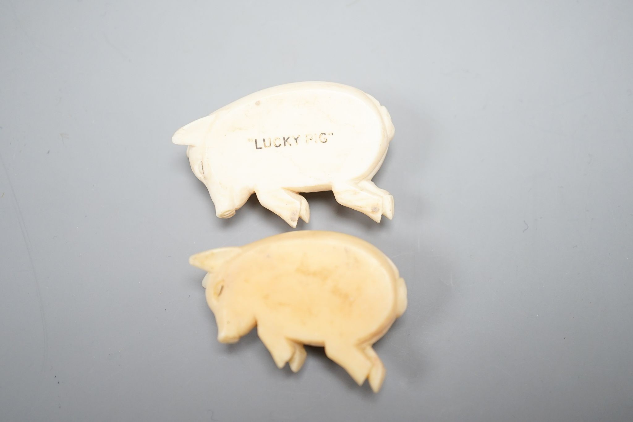 Two ivory sleeping pigs., 5 cms wide